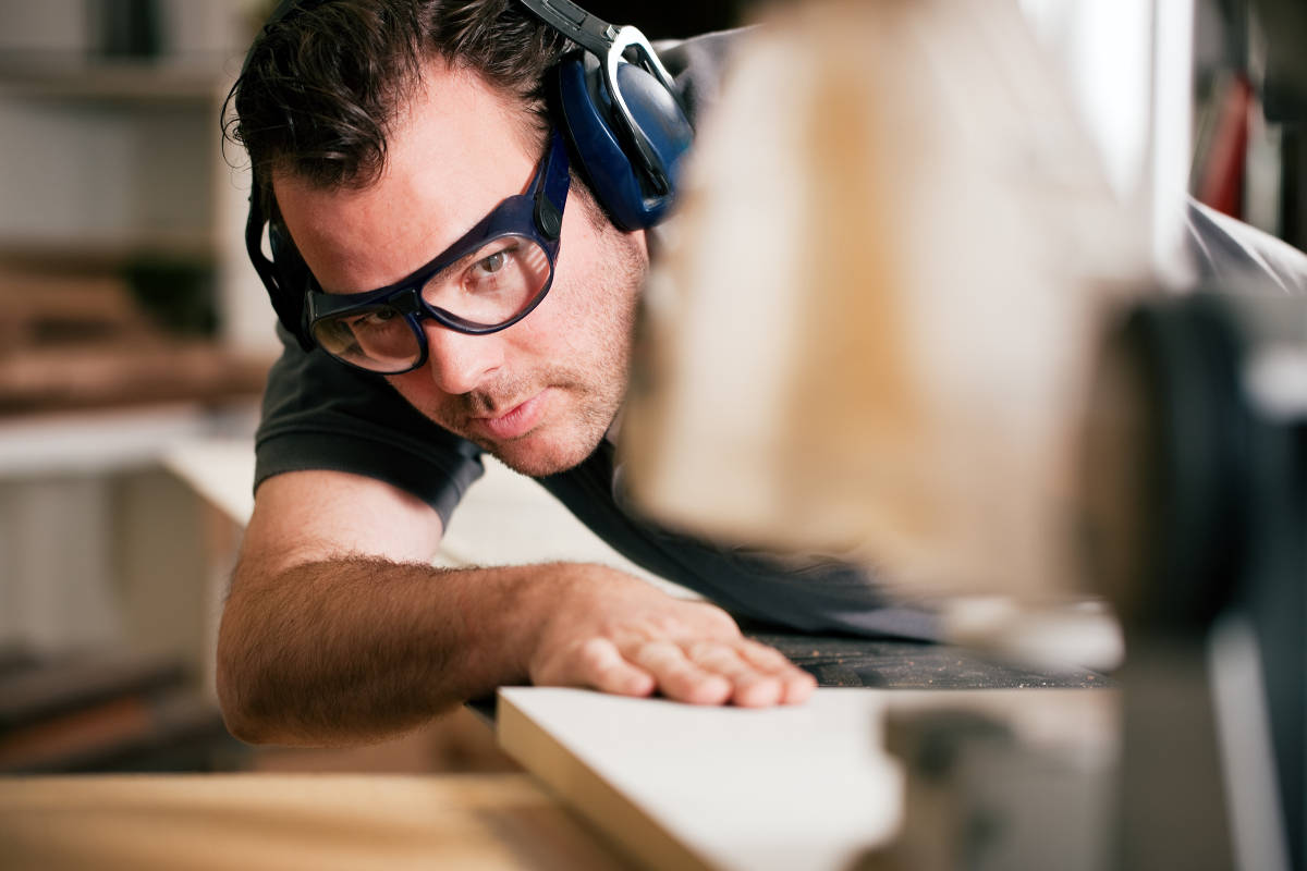 man at work practicing eye saftey by wearing saftey goggles while sawing wood